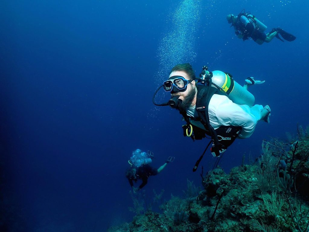 Mark Cleveland scuba diving over a reef with two dive partners
